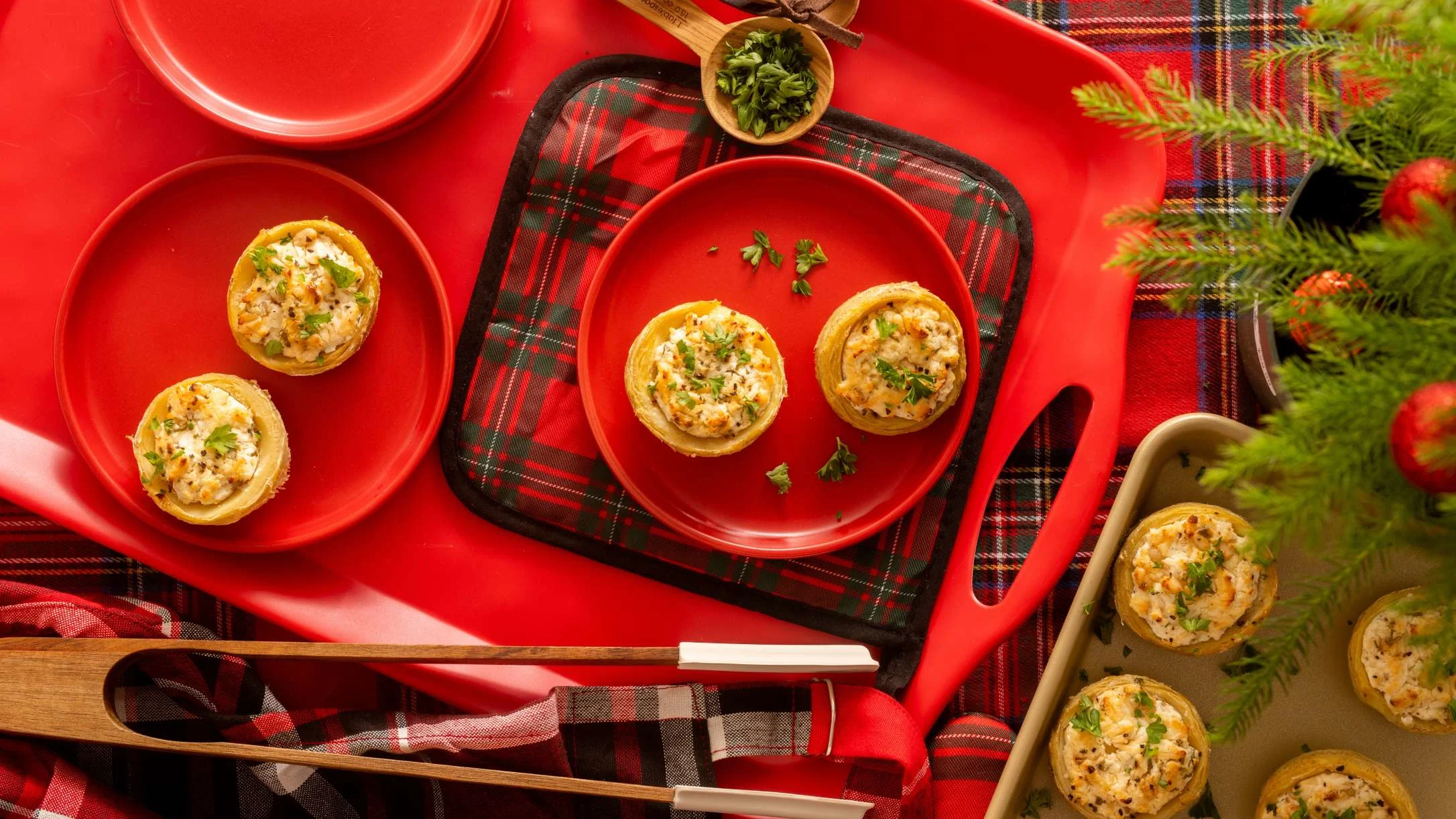 Savory appetizer on red plates with plaid tablecloth and Christmas greenery, festive holiday party spread.